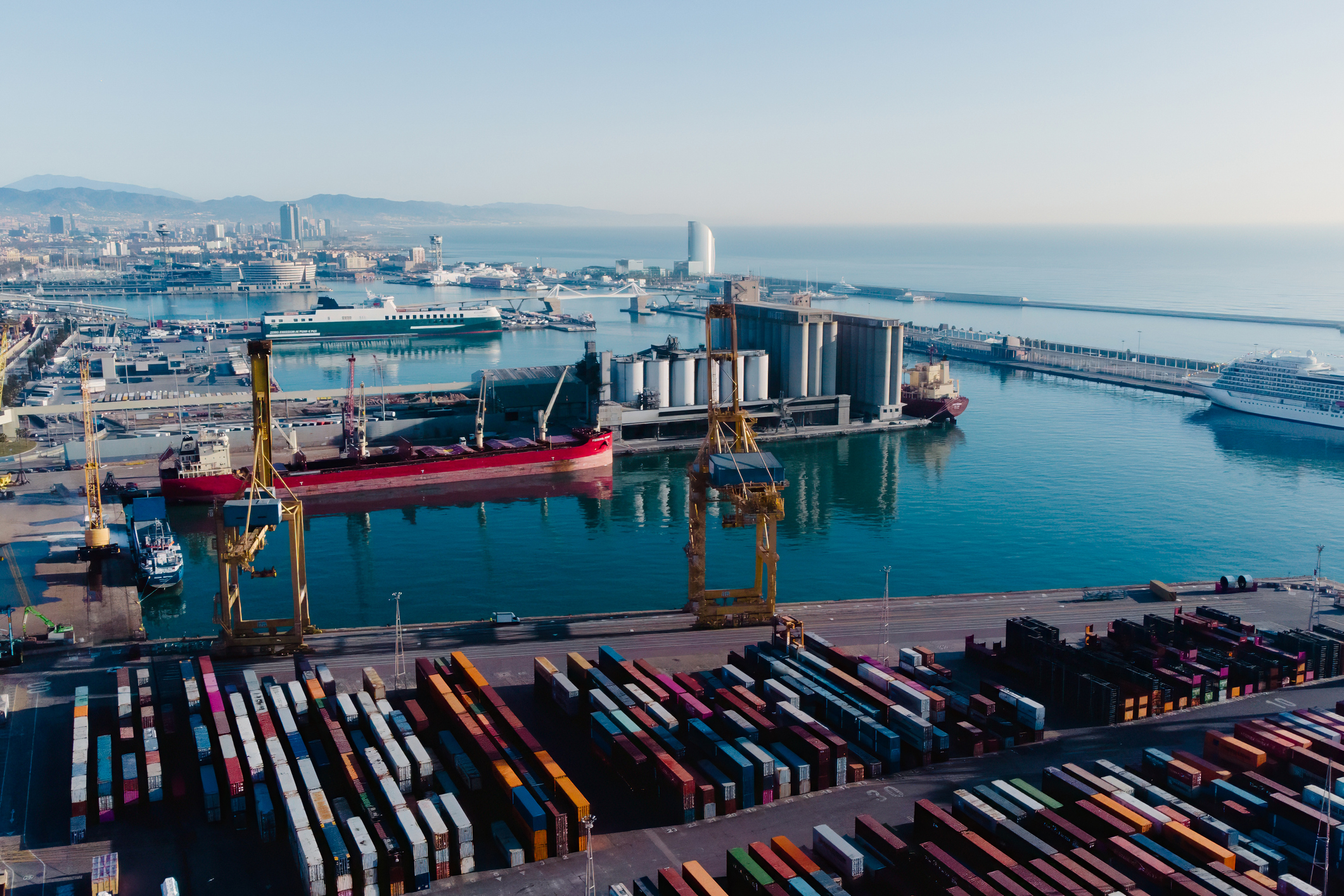 Aerial view of shipping containers and cargo ships in the sea port of Barcelona in Spain, Europe. Concept of sea and maritime trade and trade war due to tariffs. Commercial hub